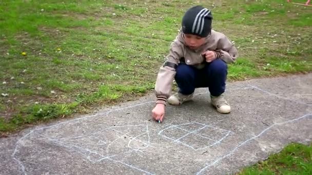 Creatividad infantil. Chico dibuja con tiza en el pavimento . — Vídeo de stock