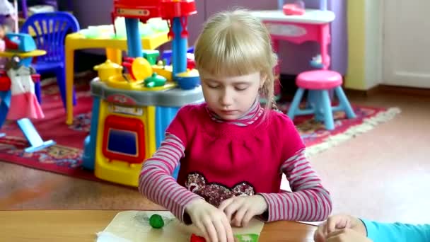 女孩在幼儿园处理建模的橡皮泥。她是非常认真、 专注，而且热衷于最喜欢的消遣。它给她带来快乐 — 图库视频影像