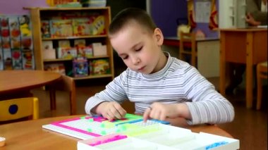 Yakından bir masa oyunu yapan anaokulu çocuk. Çok ciddi, odaklı ve en büyük eğlencesi hakkında tutkulu olduğunu. Onu zevk getiriyor.