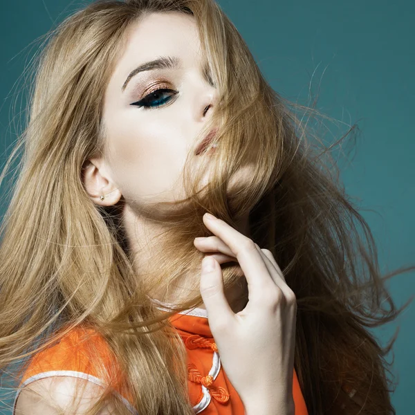 Portrait d'une belle femme blonde aux cheveux longs dans un studio sur fond bleu en vêtements jaunes, le concept de santé et de beauté — Photo