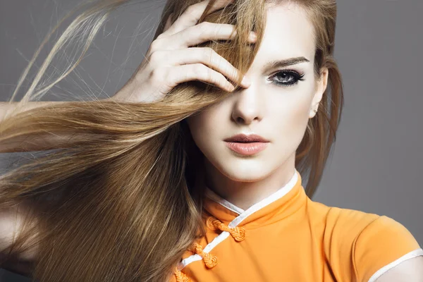 Porträtt av en vacker blond flicka i studion på en grå bakgrund med att utveckla hår, begreppet hälsa och skönhet — Stockfoto