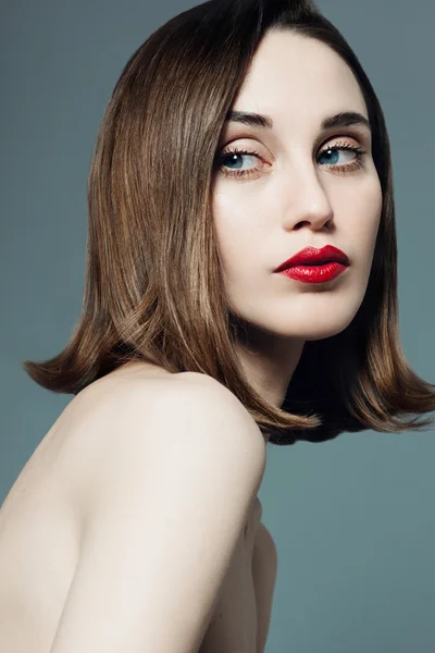 Portret van een jonge mooi meisje met rode lippenstift in de studio op een grijze achtergrond — Stockfoto