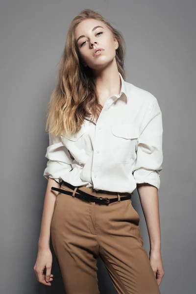 Retrato de una hermosa mujer rubia con una camisa blanca en el estudio sobre un fondo gris —  Fotos de Stock