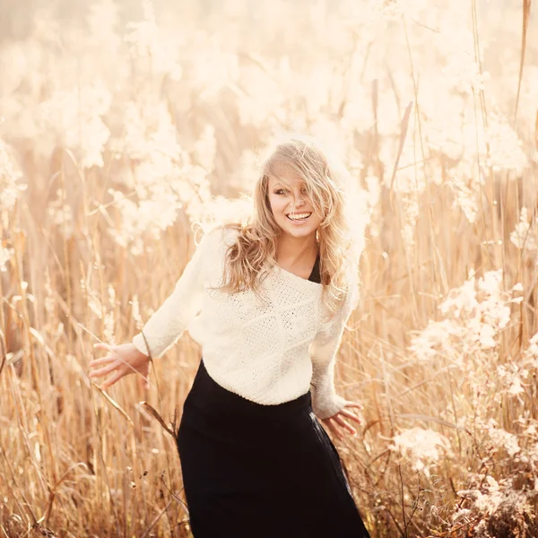 Portrait d'une belle jeune fille blonde dans un champ en pull blanc, souriant, concept de beauté et de santé — Photo