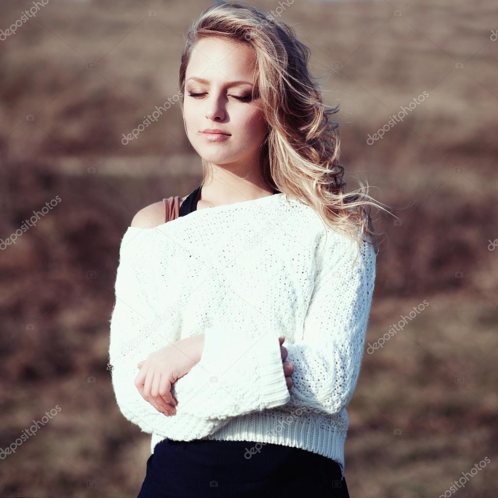 Portrait of a beautiful young blonde girl in the white pullovers