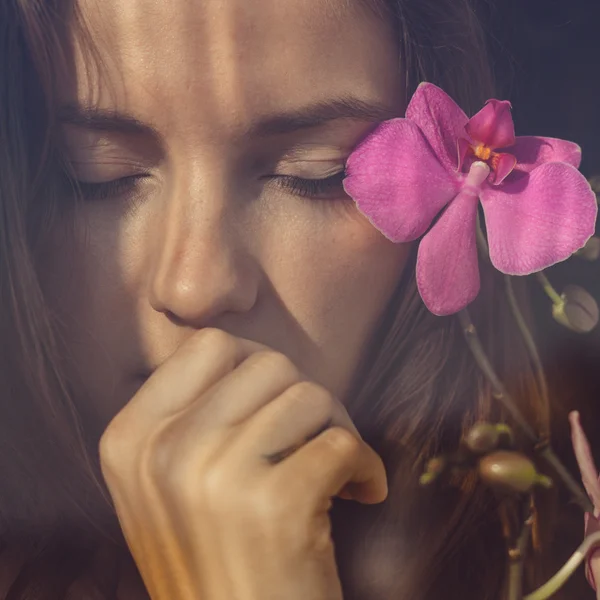 Kvinna med slutna ögon och blomma i håret — Stockfoto