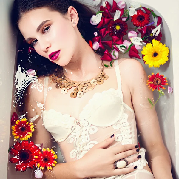 Chica morena con flores en el agua —  Fotos de Stock