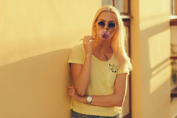 Donna in occhiali da sole che tiene il fiore vicino a labbra — Foto Stock