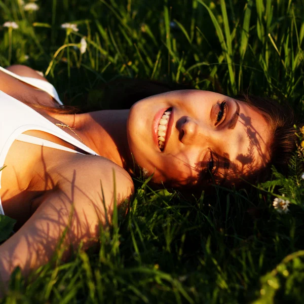 Lächelnde Frau im Gras liegend — Stockfoto