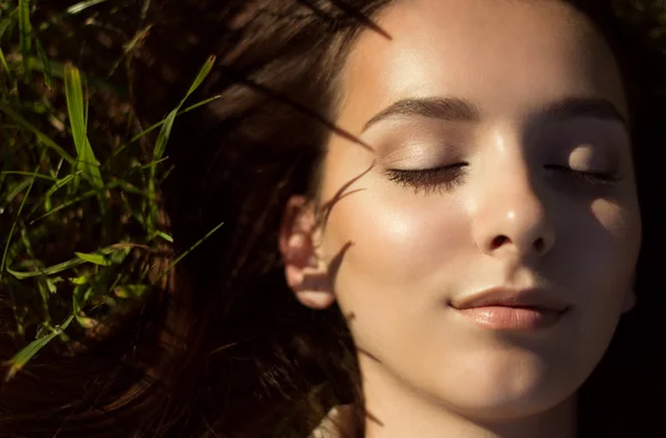 Kobieta z zamkniętymi oczami, leżąc na trawie — Zdjęcie stockowe