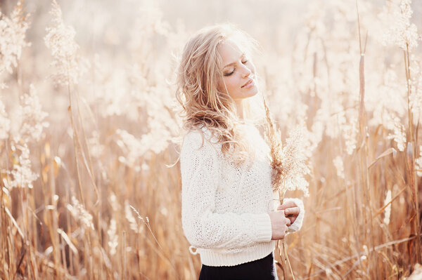 Portrait of beautiful young girl in an autumn field in white pullover, life style