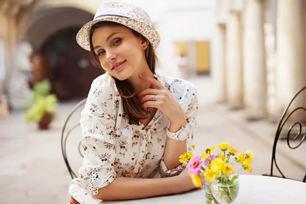 Fille assise à une table dans un chapeau — Photo