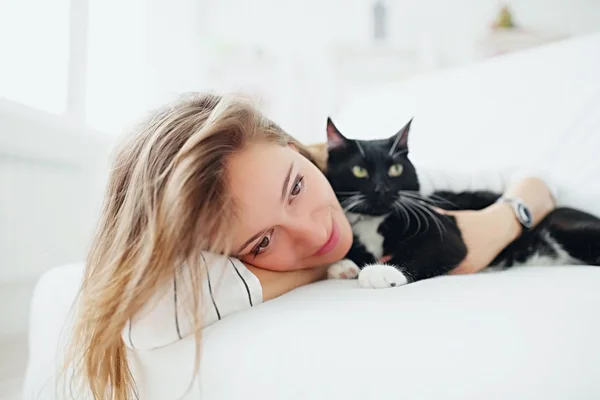 Meisje met kat liggend op het bed — Stockfoto