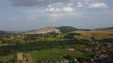 Tepeleri, ormanı ve köyü olan bir panorama.