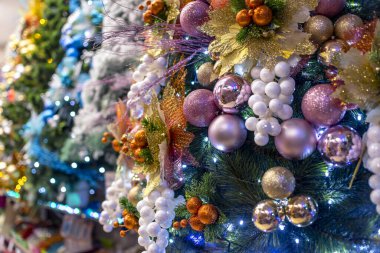 Süslerle, toplarla ve LED ışıklarla süslenmiş renkli vinil Noel ağaçları dizilimi. Yerel bir mağazada ya da mağazada satışta.