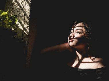 Derin melankolik düşüncelere sahip Asyalı genç bir bayanın dramatik ve sade bir görüntüsü. Üzüntü ve yalnızlık kavramı.