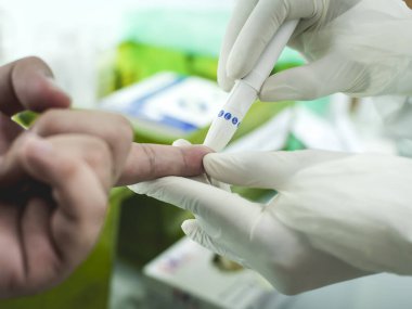 Parmak delici kan testinin yakın görüntüsü. Bir hasta hızlı antikor testi ile tek kullanımlık kan neşteri kullanılarak Covid-19 için test edilir. Kan şekeri için de test yapılabilir..