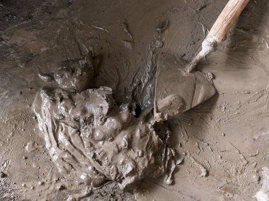 Yakınlarda bir malası olan küçük bir çimento yığını. Beton zemine dikkatsizce yerleştirilmiş. Fayanslar, tamirat ya da DIY için küçük bir proje.