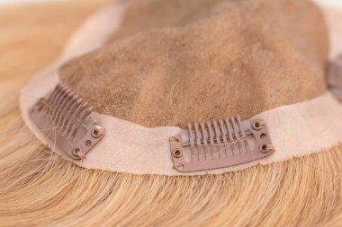 Closeup of snap-comb or wig clips on a light brown toupee. clipart