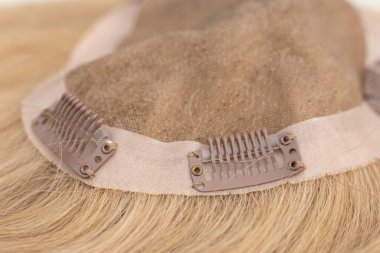 Closeup of snap-comb or wig clips on a light brown toupee. clipart