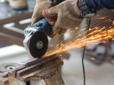 Bir açı öğütücüsünün metal bir çubuğu kesmesi. Kıvılcımlar uçuşuyor.
