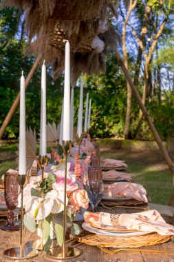 Açık hava bahçe düğününde güzel bir kır sofrası. Beyaz uzun mumlar. Açık hava ziyafeti, dışarıda.