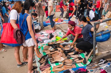 Divisoria, Manila, Filipinler - Ekim 2020: Bir anne ve kızı kaldırımda ayakkabı ve gömlek satıyor. Filipinler 'de sokak satıcılığı.