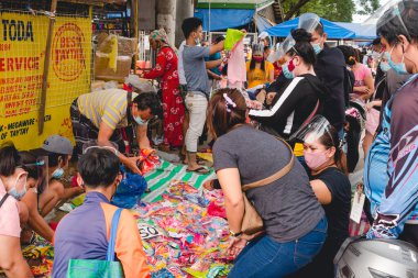 Divisoria, Manila, Filipinler - Ekim 2020: Müşterilerin bir sokak satıcısından çocuk gömleği satın aldığı bir sahne. Hepsi maske takıyor ama sosyal mesafeyi zar zor gözlemliyorlar. Hareketli tiangge sahnesi.