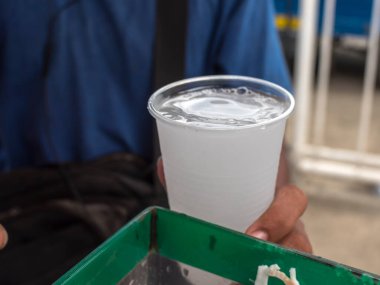 Bir sokak satıcısı plastik bir bardak Buko Juice tutuyor. Hindistan cevizi suyu olarak da bilinir, Filipinler 'de popüler bir içecektir..