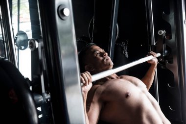 Odaklanmış ve kararlı Asyalı bir adamın spor salonunda ya da fitness merkezinde Smith Machine 'e eğimli bank baskısı yapması..