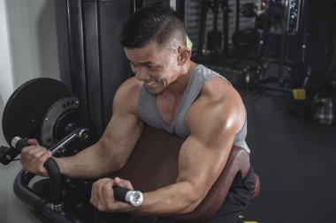 İyi yapılı ve formda Asyalı bir adam spor salonunda ya da fitness kulübünde vaaz veriyor. Yüksek açılı atış. Kol ve pazı egzersizi..