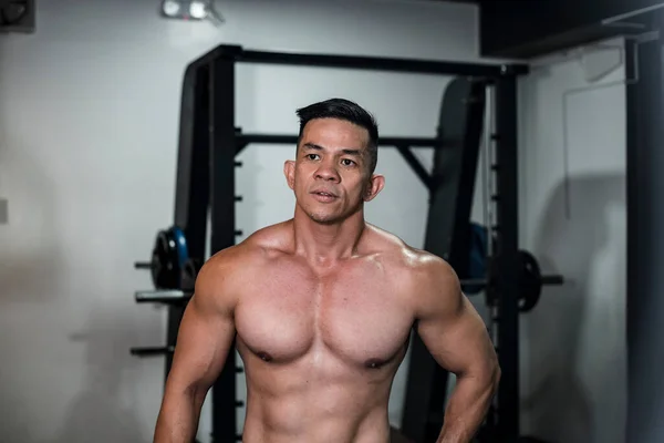 A buff, sexy and fit 40 year old asian fitness model at the gym or health club. Healthy living for middle aged men concept.