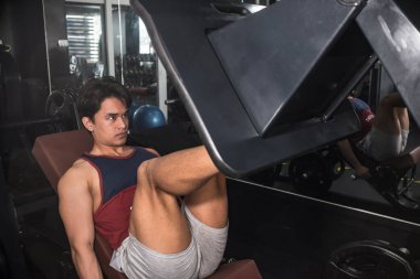 Kararlı ve odaklanmış Asyalı bir atlet bacak pres makinesinde dörtlü çalışıyor..