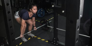 Atletik bir Asyalı kadın spor salonunda birkaç kaldırma işlemi yapmaya hazırlanıyor. Metin için sağdaki metin boşluğu.
