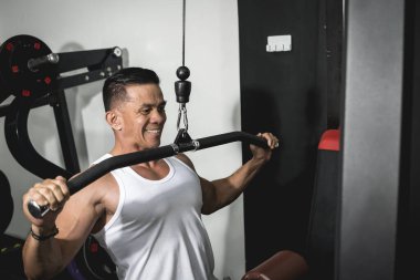 Beyaz atletli Asyalı bir adam sırt kaslarını çalıştırıyor. Yoğun egzersiz kavramı.