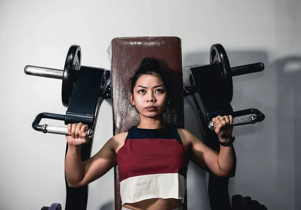 一个活泼的亚洲女孩做一些机器肩压 在体育馆做熟食 — 图库照片