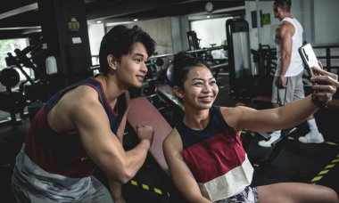 Genç Asyalı bir çift spor salonunda iyi vakit geçiriyorlar ve idmandan sonra selfie çekiyorlar..