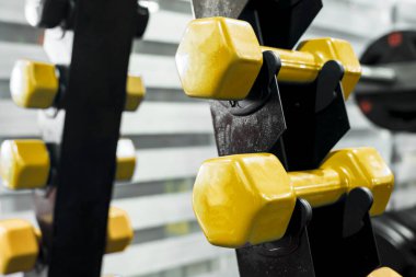 Dikey halterde duran sarı plastik halterlerin yakın çekimi. Spor salonunda ya da spor salonunda..