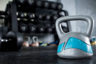 Arka planda halter askısı olan yerde ağır bir kauçuk kettlebell. Spor salonu veya sağlık kulübü ayarları.