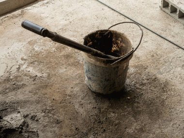 Su dolu bir kovanın içine betonun sertleşmesini önlemek için bir kürek konur..