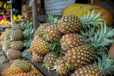 A stack of pineapples for sale at a roadside shack in Tagaytay, Philippines. A jackfruit is visible behind.