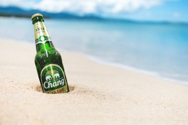 Filipinler - Aug 2020: Bir şişe Chang Birası kısmen tropikal bir plajın kenarına gömülebilir.