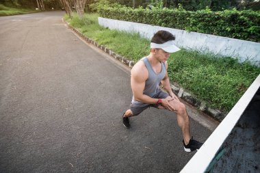 Formda ve kaslı Asyalı 40 'lı yaşlarda bir adam sabah koşusuna hazırlanmak için sokak boyunca koşar..