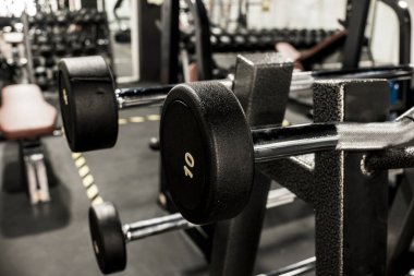 Spor salonunda ya da fitness kulübünde sabit ağırlıklı EZ ve düz halterler..