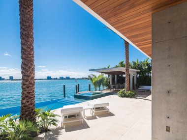 Miami Plajı - Güney Florida 'da çağdaş bir evin verandasında görülen modern bir havuz ve güneşlenme sandalyesi.