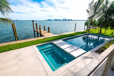 Miami Plajı, körfeze bakan küçük ahşap bir rıhtımın yanında modern bir yüzme havuzu. Güney Florida 'da lüks bir konut..