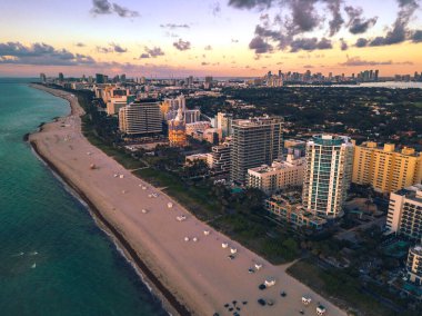 Miami Beach, Florida, Mid Beach boyunca muhteşem bir Dawn sahnesi. Sahil boyunca yerleşim yerleri ve oteller var. Arkadaki Miami silueti..