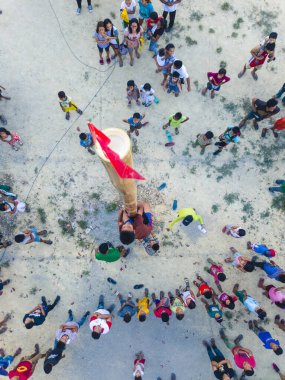 Tubigon, Bohol, Filipinler - Yağlı bir bambu direğine tırmanacak ve kalabalığın gözü önünde kırmızı bir bayrak tutacak iki çocuk. Bu Palosebo olarak bilinen bir Filipin oyunu. Filipin kültürü.