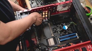 Bir bilgisayar bilişim teknisyeni bir masaüstü bilgisayarı açar ve küçük bir tornavida tutarken parçalarını inceler. Yükseltme, sorun giderme veya PC parçalarının değiştirilmesi.