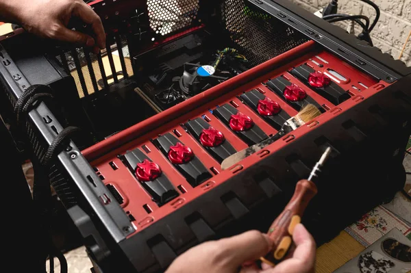 A computer technician opens up a desktop computer and inspect its parts while holding a small screwdriver. Upgrading, troubleshooting or replacing PC parts.